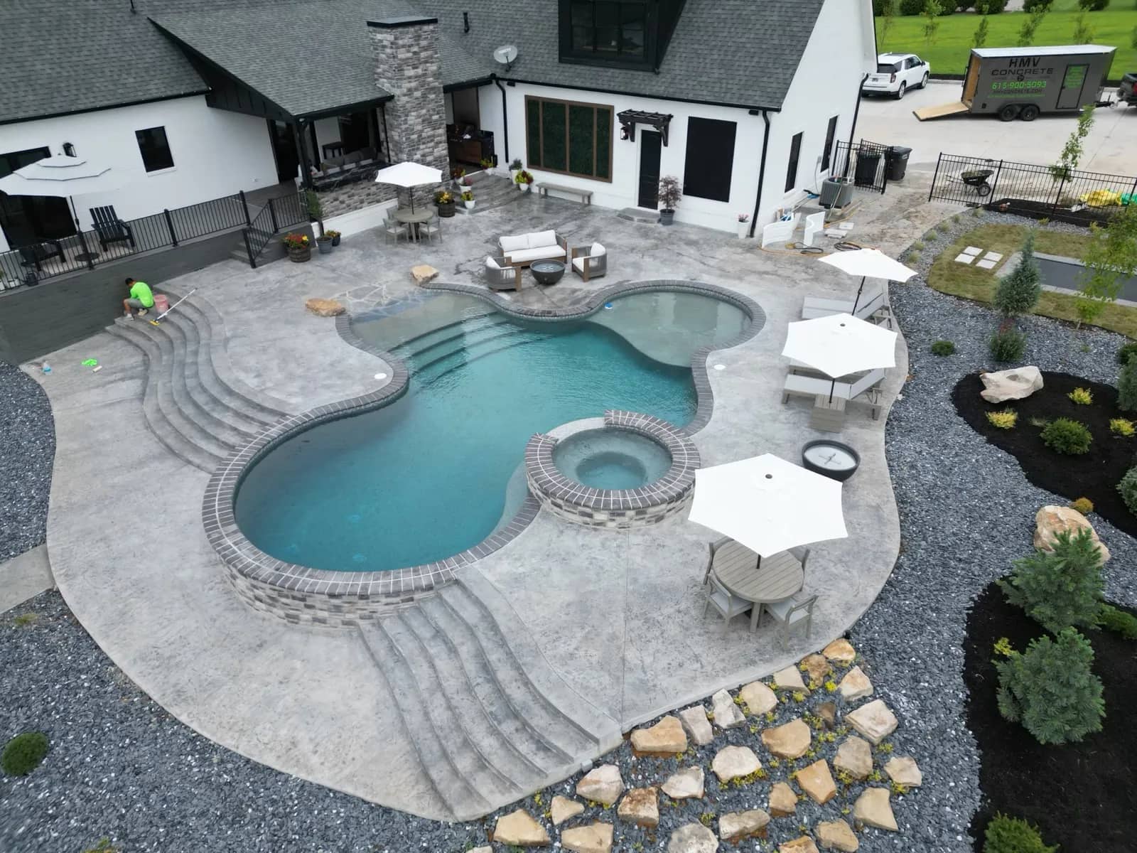 Aerial view of a freeform backyard pool and spa with a stamped-concrete patio and outdoor living in Middle Tennessee